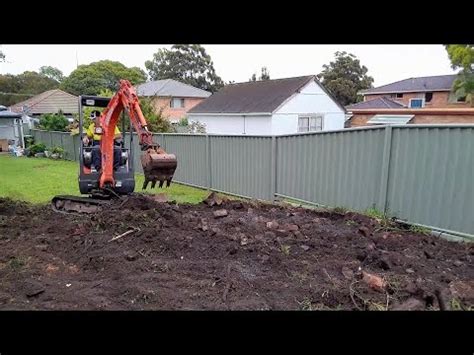 Mini Excavator excavating levelling and reshaping the yard